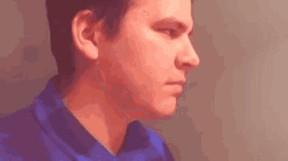 a man in a blue shirt is looking at the camera .