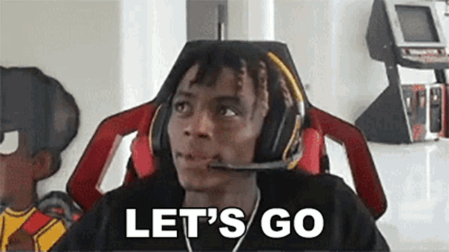 a man wearing headphones and a microphone is saying `` let 's go '' while sitting in a chair .