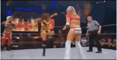 a group of women are wrestling in a ring with a referee watching .