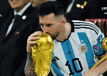 a soccer player with the number 10 on his jersey kisses a trophy