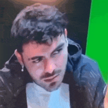 a close up of a man 's face with a green screen behind him .
