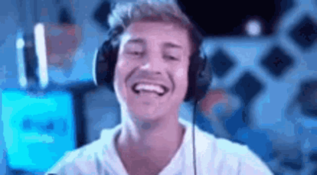 a man wearing headphones is laughing while sitting in front of a computer .