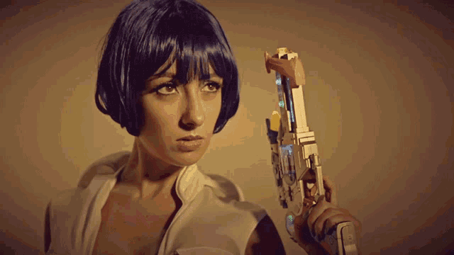 a woman in a blue wig is holding a gun with a red button on it