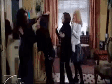 a group of women are standing in a room talking