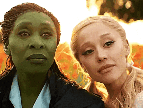 a woman with a green face and a woman with blonde hair are posing for a picture