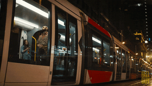 a woman looks at her phone while a man looks out the window of a train