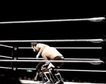 two men are wrestling in a wrestling ring with a referee watching .