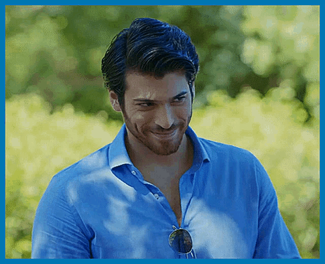a man wearing sunglasses and a blue shirt smiles for the camera