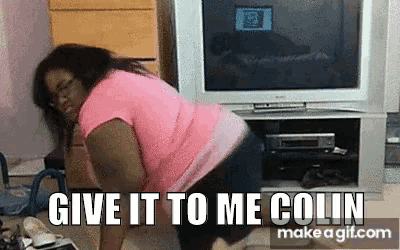 a woman in a pink shirt is dancing in front of a tv with the words give it to me colin
