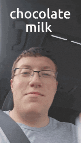 a man wearing glasses is sitting in a car with the words " chocolate milk " above him