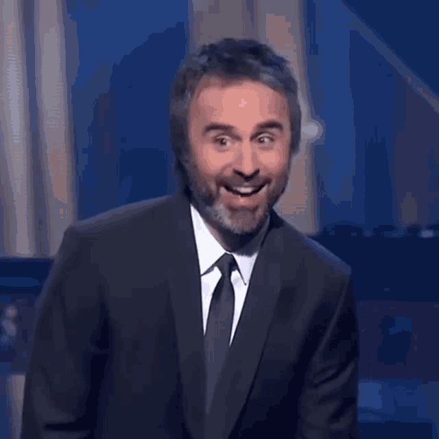 a man with a beard in a suit and tie is smiling
