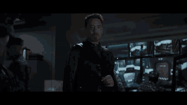 a man in a black jacket stands in a room