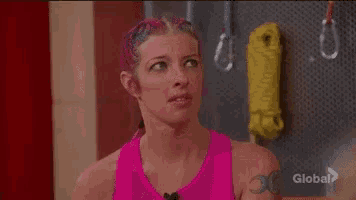 a woman with pink hair is making a funny face while standing in front of a yellow rope .
