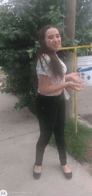 a woman standing on a sidewalk with a motorola phone in the background