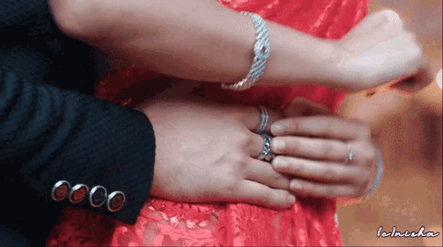 a man is putting a ring on a woman 's finger and the word lakhika is on the bottom right