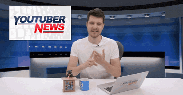 a man sitting at a desk with a youtuber news sign behind him