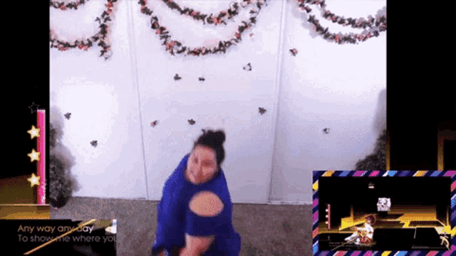 a woman in a blue dress is dancing in front of a screen that says any way anyway to show me where you