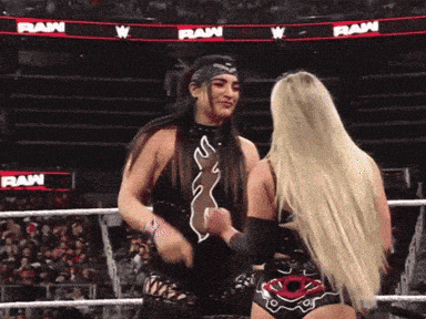 two women wrestling in a ring with a raw banner behind them