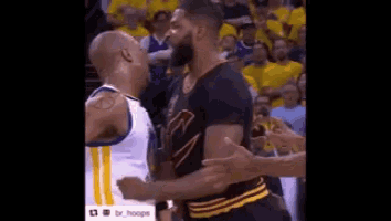 two basketball players are standing next to each other on a court . one is wearing a golden state warriors jersey .