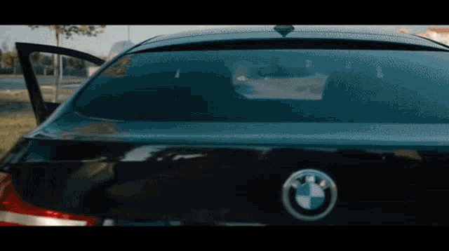 the back of a black bmw with the door open and a bmw logo