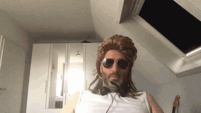 a man wearing a wig and sunglasses has a microphone on his neck