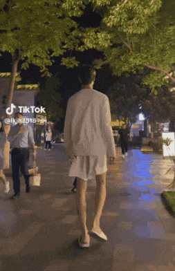 a person walking down a sidewalk with a tiktok logo on the bottom