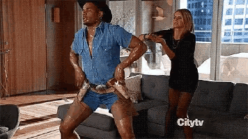 a man dressed as a cowboy is dancing in a living room with a woman standing behind him and the words citytv visible