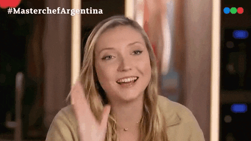 a woman is smiling and waving in front of a masterchef argentina logo