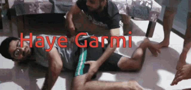 a group of men are laying on the floor with haye garmi written in red