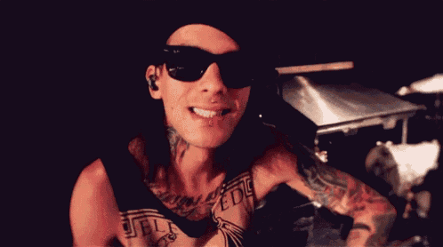 a man wearing sunglasses is giving a peace sign .