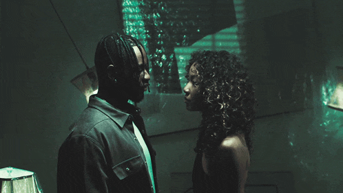 a man and woman looking at each other in a dark room