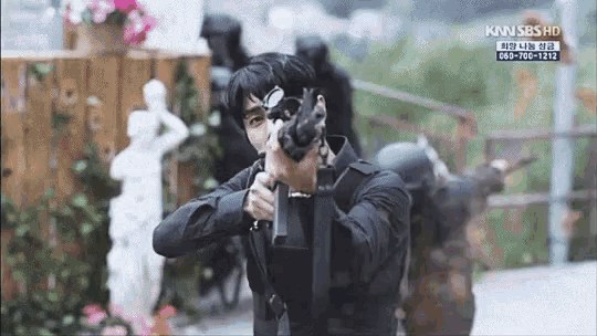 a man is holding a gun in front of a sign that says kan sbs hd on it