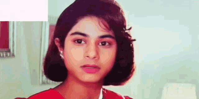 a young girl with short hair is wearing a red dress and earrings .