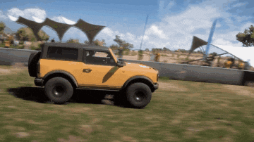 a yellow jeep is driving through a grassy area