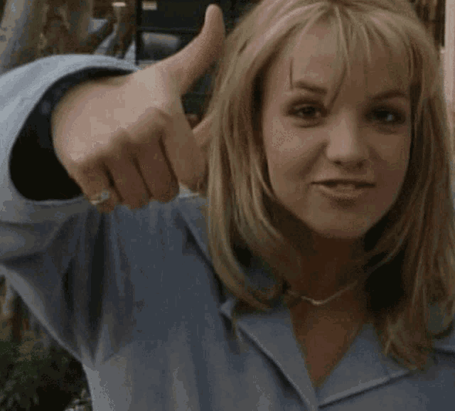 a woman is giving a thumbs up sign