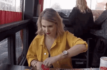 a woman in a yellow jacket is sitting at a table with a can of coca cola