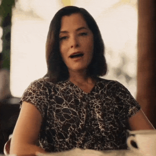 a woman is sitting at a table with a cup of coffee in front of her .