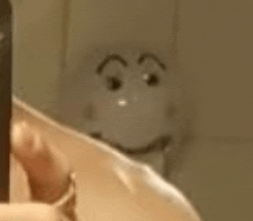 a close up of a person holding a knife in front of a toilet with a smiley face on it .