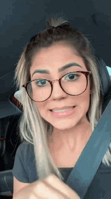 a woman wearing glasses is smiling while sitting in a car seat