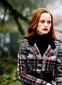 a woman with red hair wearing a plaid jacket and black turtleneck .