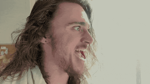a man with long hair and a beard making a face
