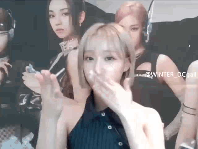 a woman is blowing a kiss in front of a group of girls .