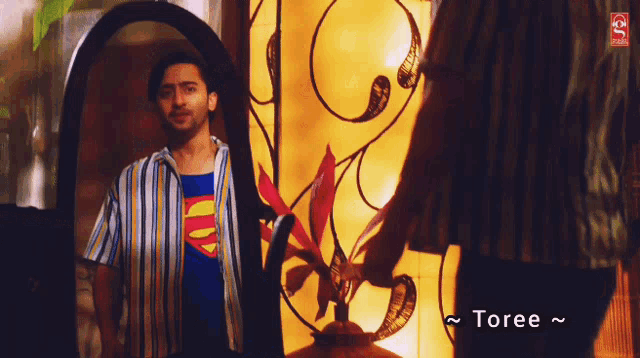 a man in a superman shirt is looking at himself in the mirror