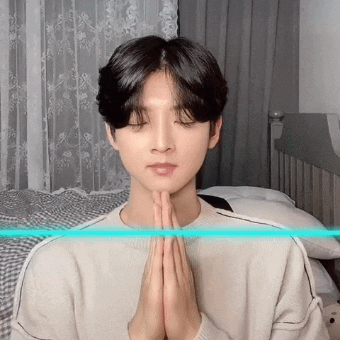 a young man is praying with his hands folded in front of his face