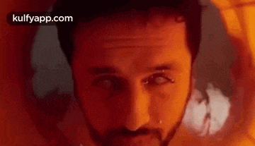 a close up of a man 's face with a beard and a piercing in his nose .