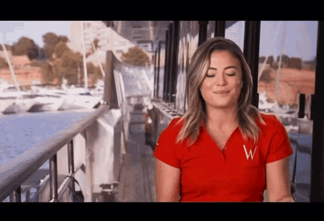 a woman in a red shirt is standing on the deck of a boat .