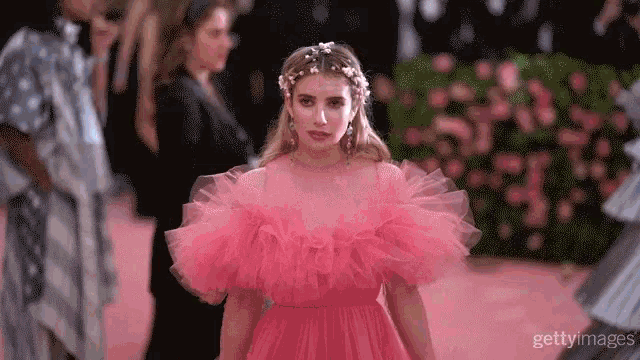 a woman in a pink dress with ruffled sleeves is walking down a runway
