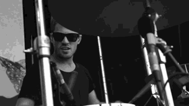 a man wearing sunglasses is playing drums in front of a microphone