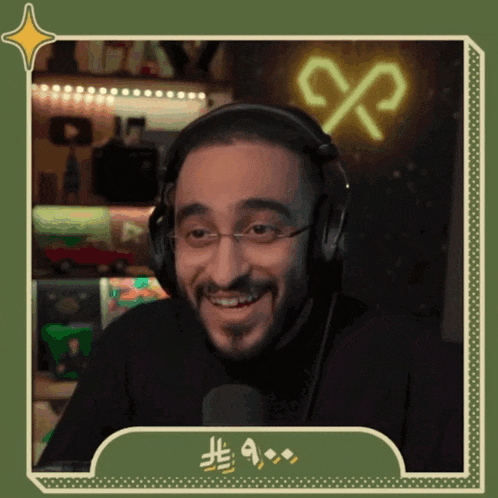 a man wearing headphones and glasses is smiling in front of a microphone