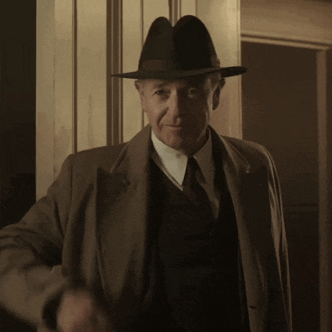a man wearing a hat and a coat stands in a doorway